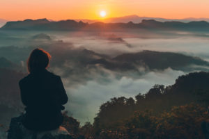 Image of a person looking out at the setting sun and a cloudy landscape. If you are needing anxiety help we are here for you. We off a holistic approach to anxiety treatment that will reduce your anxiety symptoms. Reach out now to see how anxiety therapy can help. Call today!
