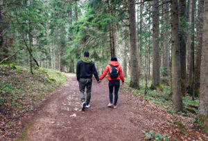 Imagen de una pareja caminando juntos entre árboles altos. Representando a personas que podrían beneficiarse de la terapia de pareja en español con un consejero matrimonial en Colorado Springs, CO.