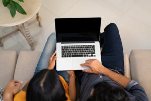 A couple type on a laptop together, representing the support online couples counseling in Colorado can offer. Learn more about marriage counseling Colorado Springs by contacting a Colorado Springs couples therapist today. 