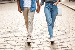 A couple hold hands while walking down a brick road. This could symbolize the bonds cultivated by working with a Colorado Springs couples therapist. Learn more about online couples counseling today. 